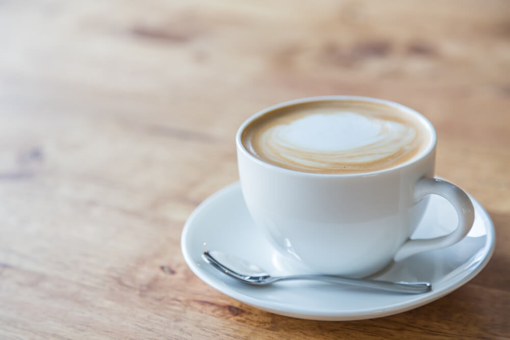 Cappuccino in einer Tasse mit Untertasse auf einem Holztisch